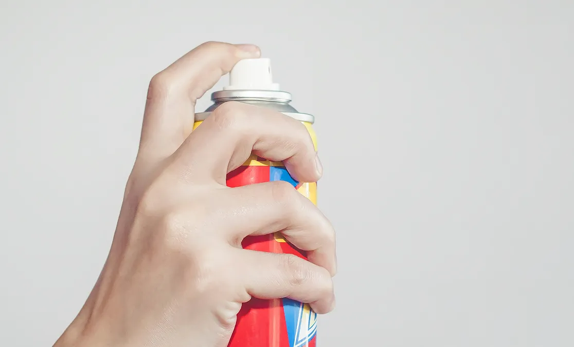 スプレー缶を握り、空中に向けて噴射しようとしている手元の様子