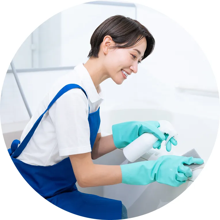 青い手袋をはめた手でスポンジを使って浴室を清掃している様子