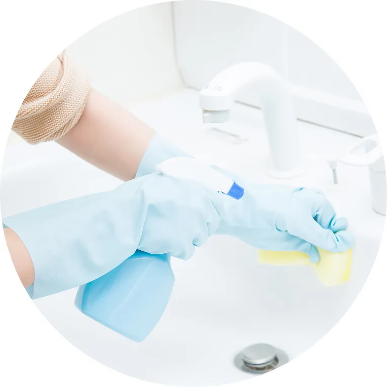 スプレーボトルとスポンジで洗面所を清掃している様子